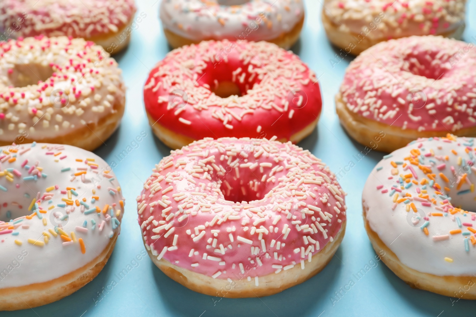 Photo of Delicious glazed doughnuts with sprinkles on color background