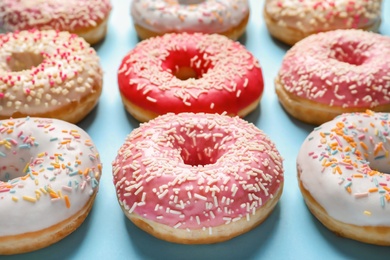 Delicious glazed doughnuts with sprinkles on color background