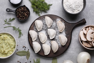 Photo of Raw dumplings (varenyky) and ingredients on grey table, flat lay