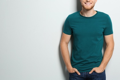 Young man wearing blank t-shirt on light background, closeup. Mockup for design
