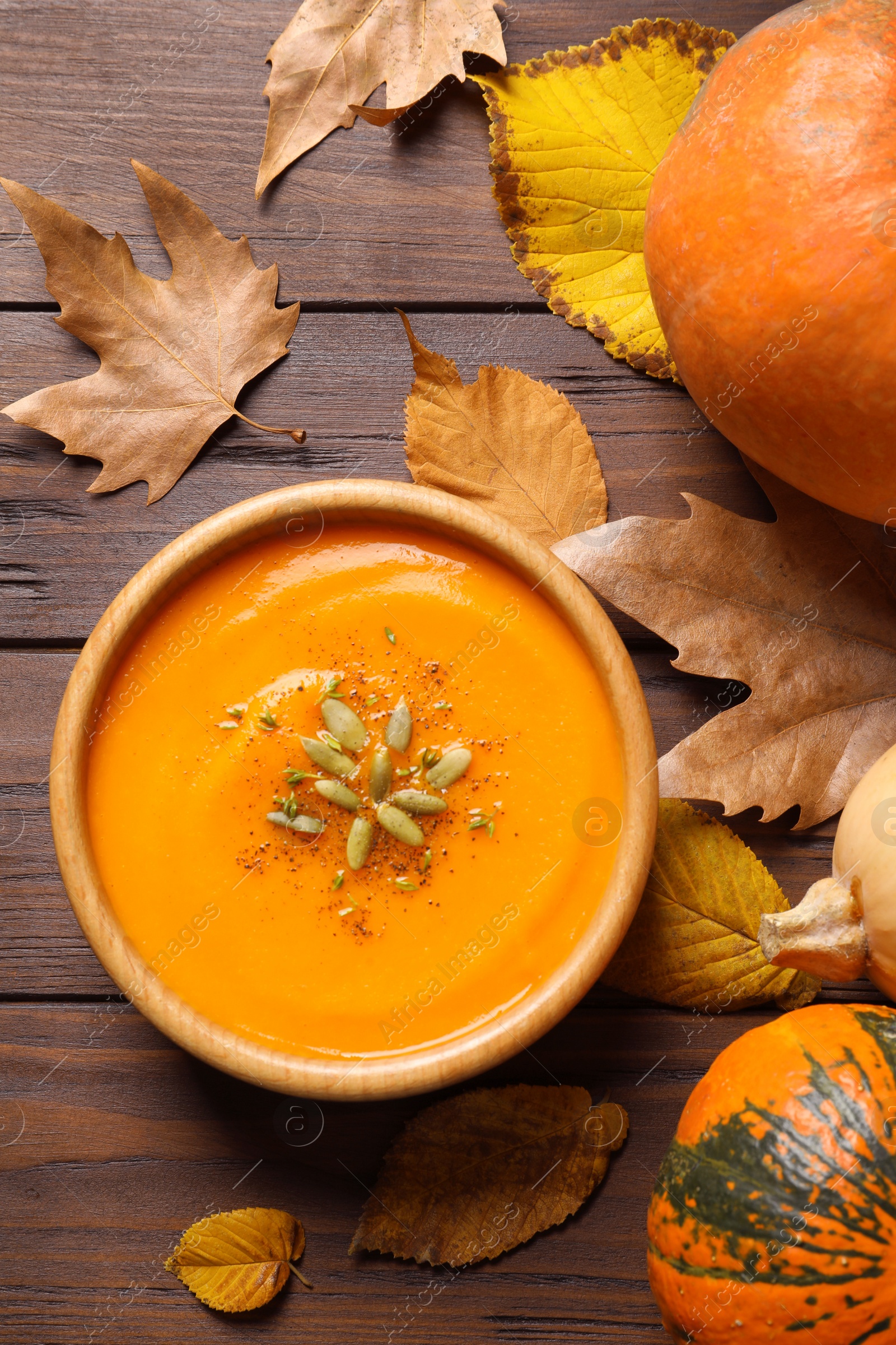 Photo of Flat lay composition with bowl of pumpkin soup on wooden background