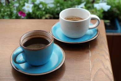 Cups of fresh aromatic coffee on wooden table