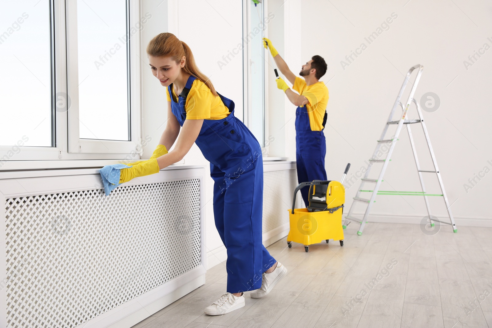 Photo of Professional janitors in uniform cleaning spacious room