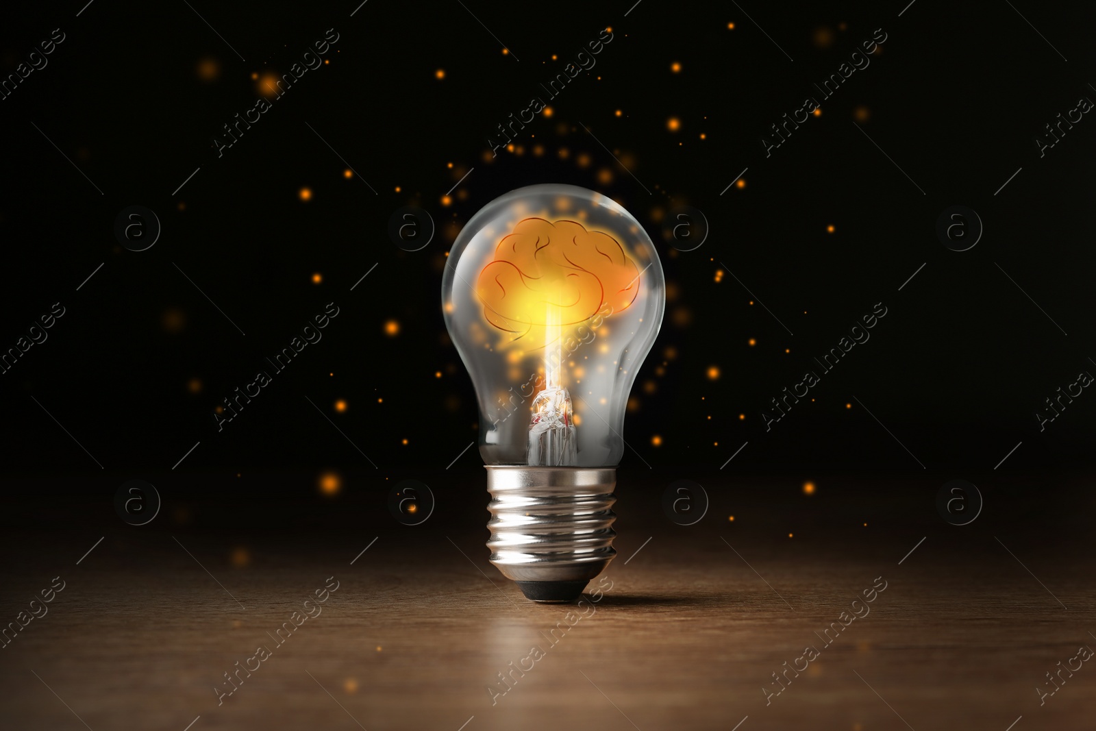 Image of Lamp bulb with shining brain inside on wooden table against black background. Idea generation