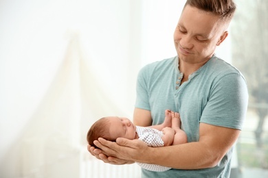 Photo of Man holding his newborn baby at home. Space for text
