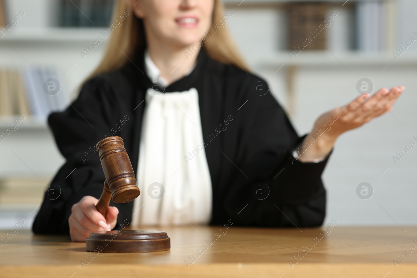 Photo of Judge striking mallet at wooden table in courtroom, closeup