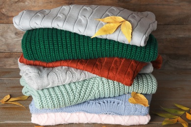 Photo of Stack of sweaters on wooden background. Autumn clothes