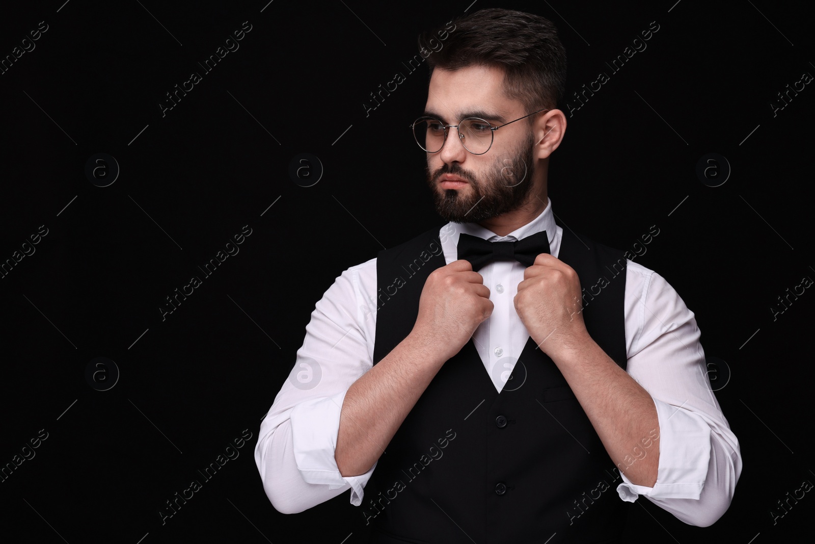 Photo of Portrait of handsome man in shirt and bow tie on black background. Space for text