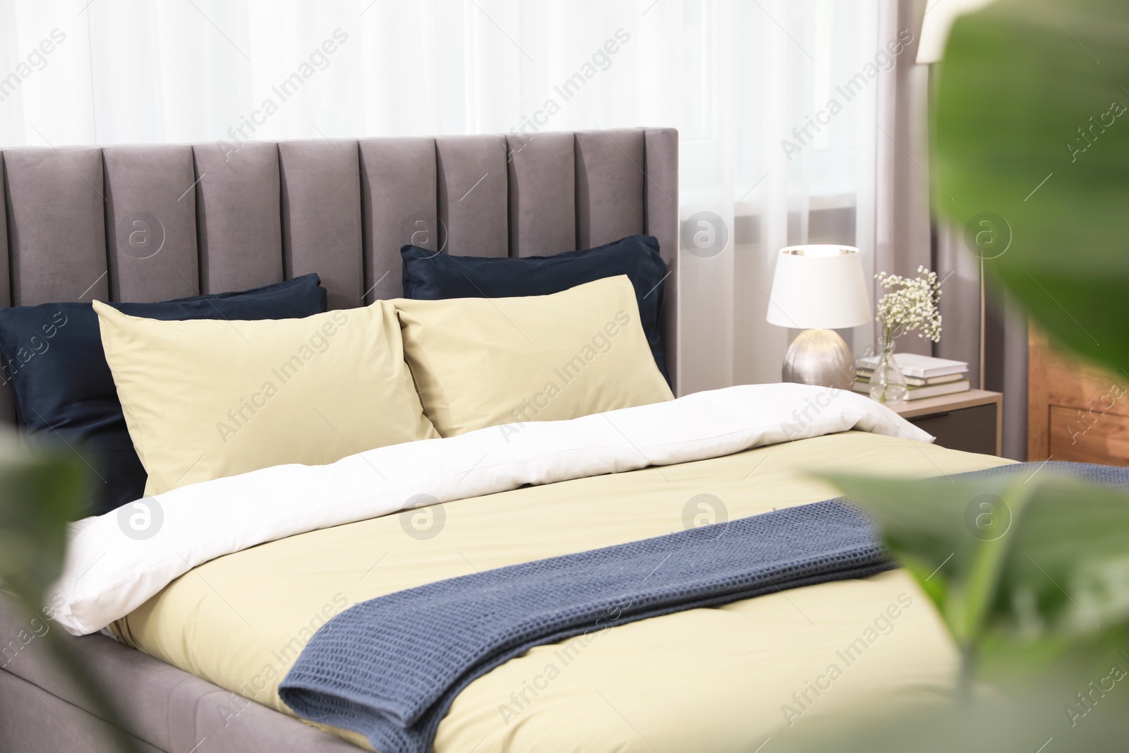 Photo of Comfortable bed with cushions and bedding in room. Stylish interior