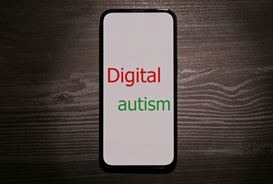 Photo of Smartphone with phrase Digital Autism on wooden table, top view. Addictive behavior