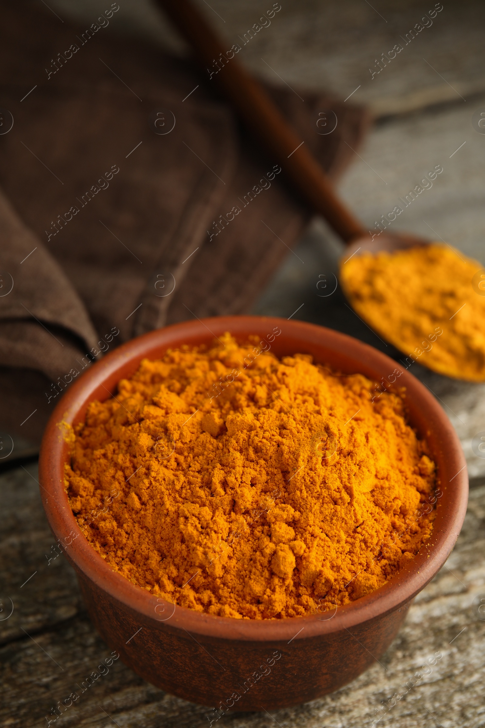 Photo of Bowl and spoon with saffron powder on wooden table