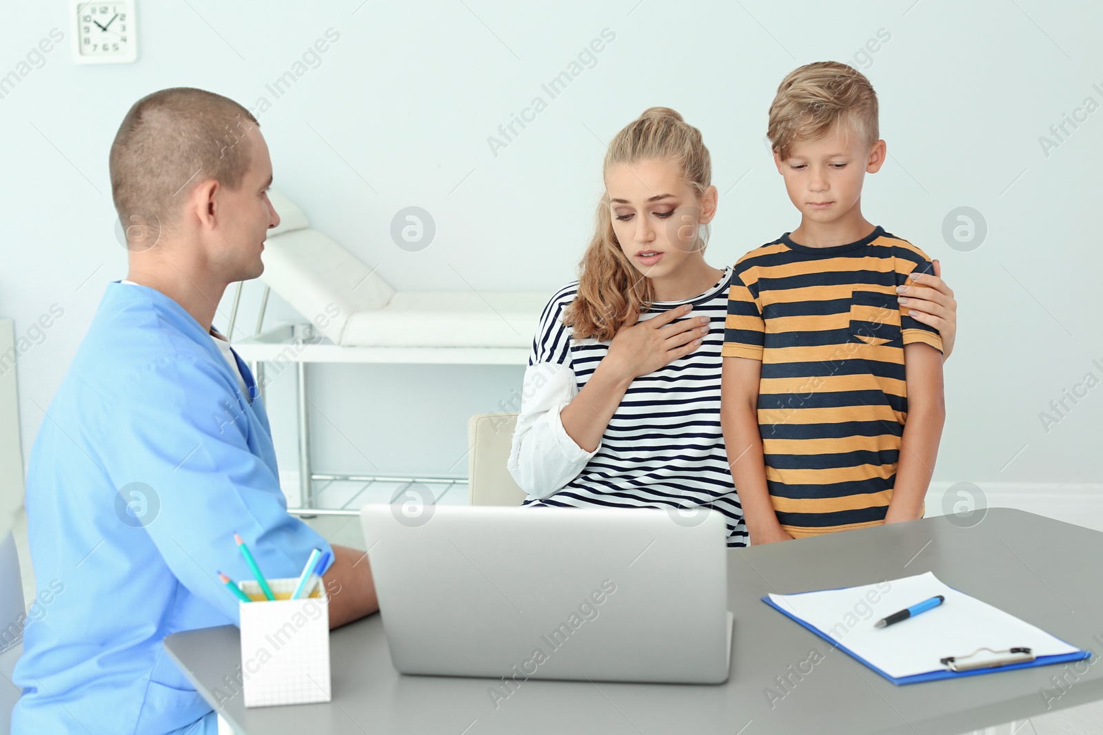 Photo of Male medical assistant consulting mother with son in clinic