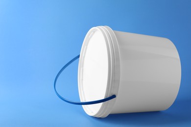 One plastic bucket with lid on light blue background. Space for text