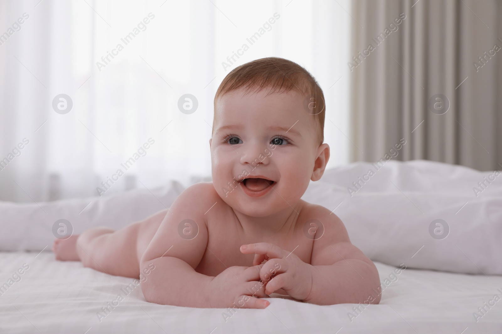 Photo of Cute little baby lying on bed with soft blanket indoors