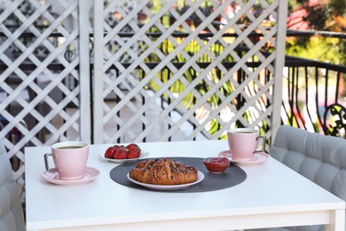 Photo of Outdoor breakfast with tea and croissants on white table on terrace