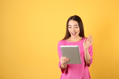 Photo of Woman using tablet for video chat on color background. Space for text