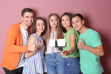 Young happy friends taking selfie against color background