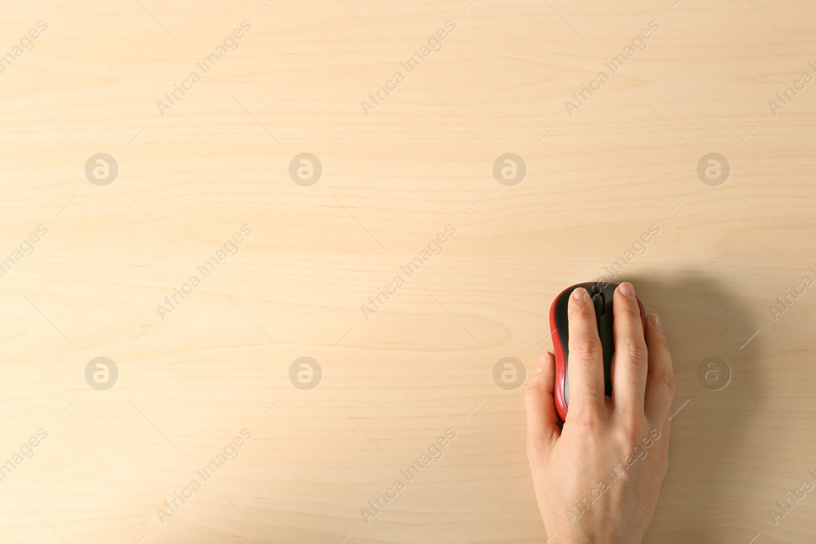 Photo of Woman using computer mouse on wooden background, top view. Space for text