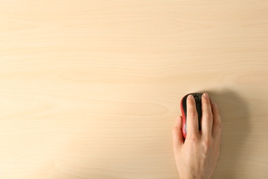 Photo of Woman using computer mouse on wooden background, top view. Space for text