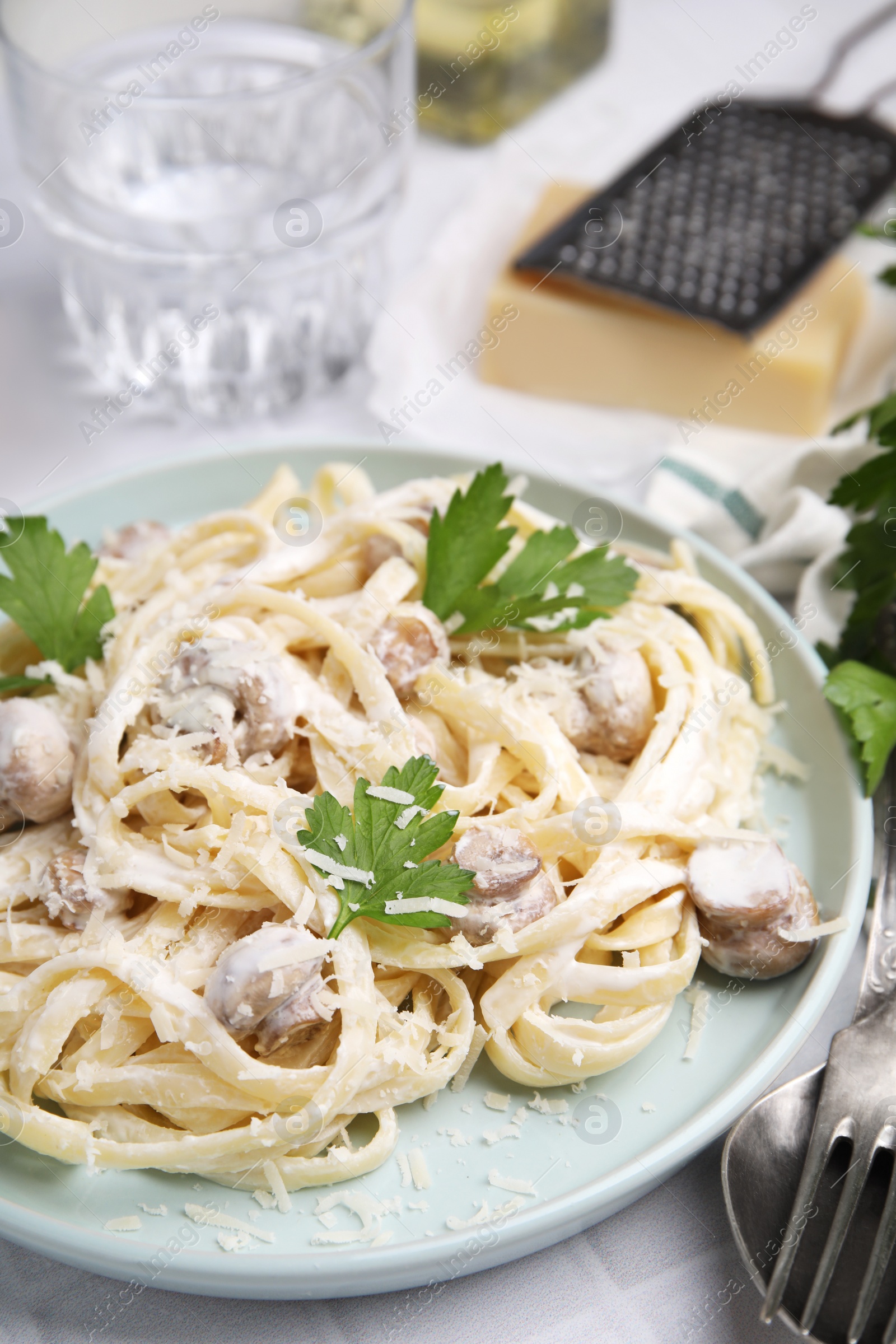 Photo of Delicious pasta with mushrooms on white tiled table, closeup