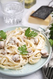 Photo of Delicious pasta with mushrooms on white tiled table, closeup