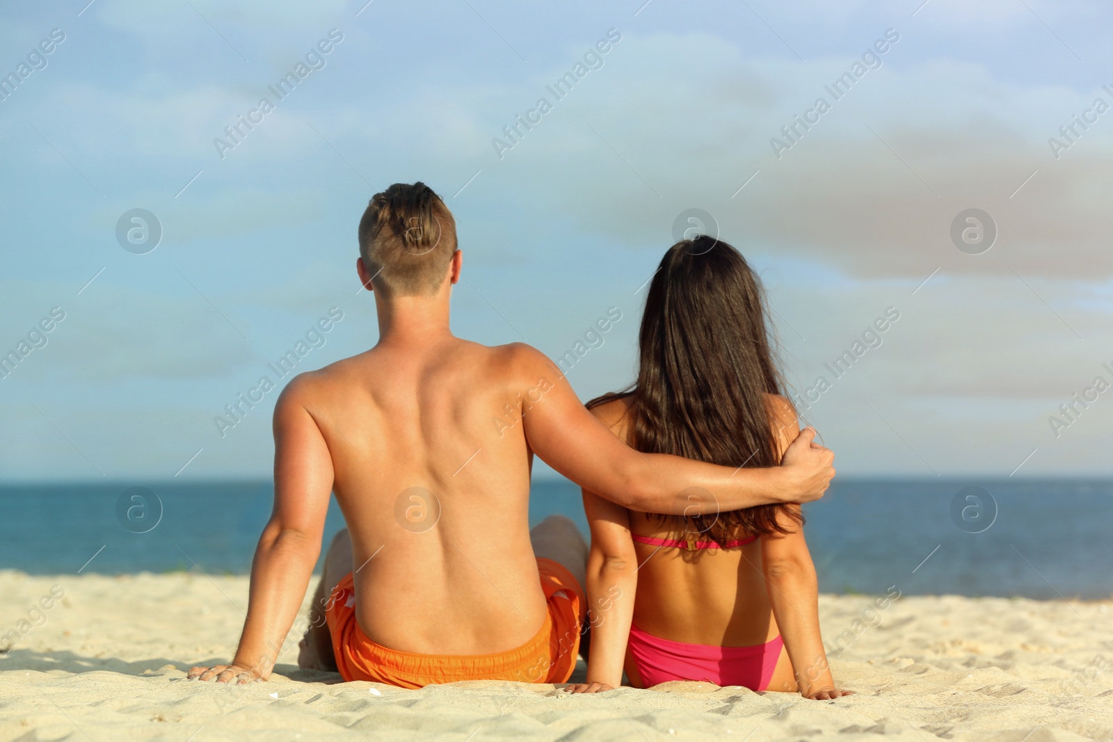 Photo of Young woman in bikini spending time with her boyfriend on beach. Lovely couple