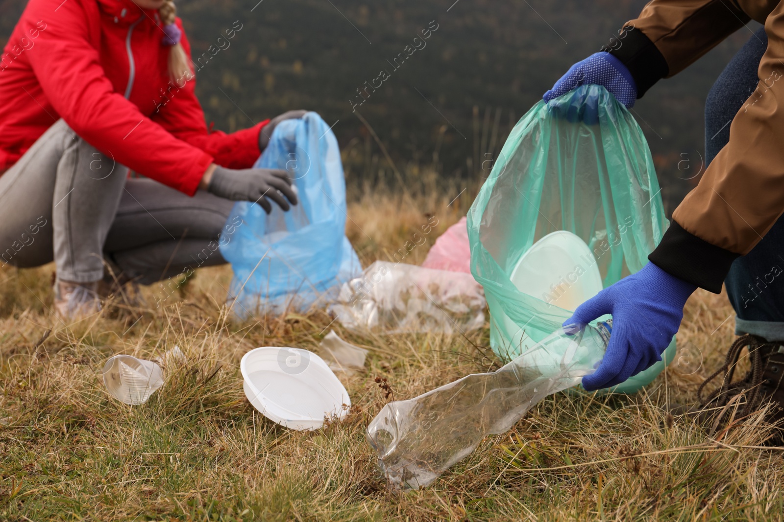 Photo of People with trash bags collecting garbage in nature, closeup