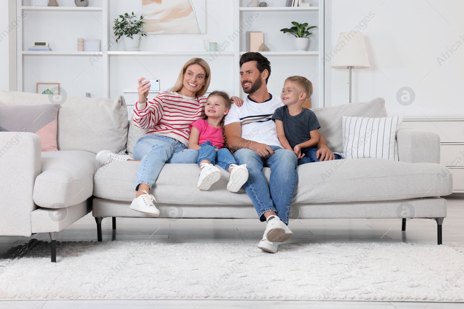 Photo of Happy family taking selfie together on sofa at home