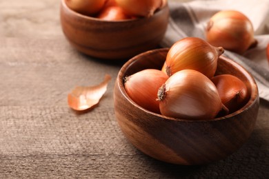Many ripe onions on wooden table, closeup. Space for text
