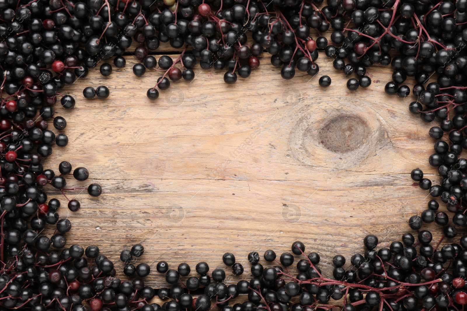 Photo of Frame of black elderberries (Sambucus) on wooden table, flat lay. Space for text