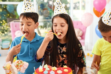 Photo of Happy children eating delicious cake at birthday party indoors