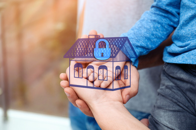 Home security concept. Family holding house indoors, closeup