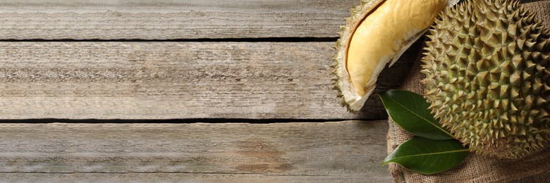 Image of Fresh ripe durian fruits on wooden table, top view with space for text. Banner design