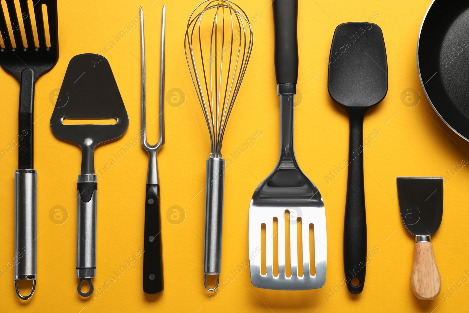 Photo of Different spatulas and other kitchen utensils on orange background, flat lay