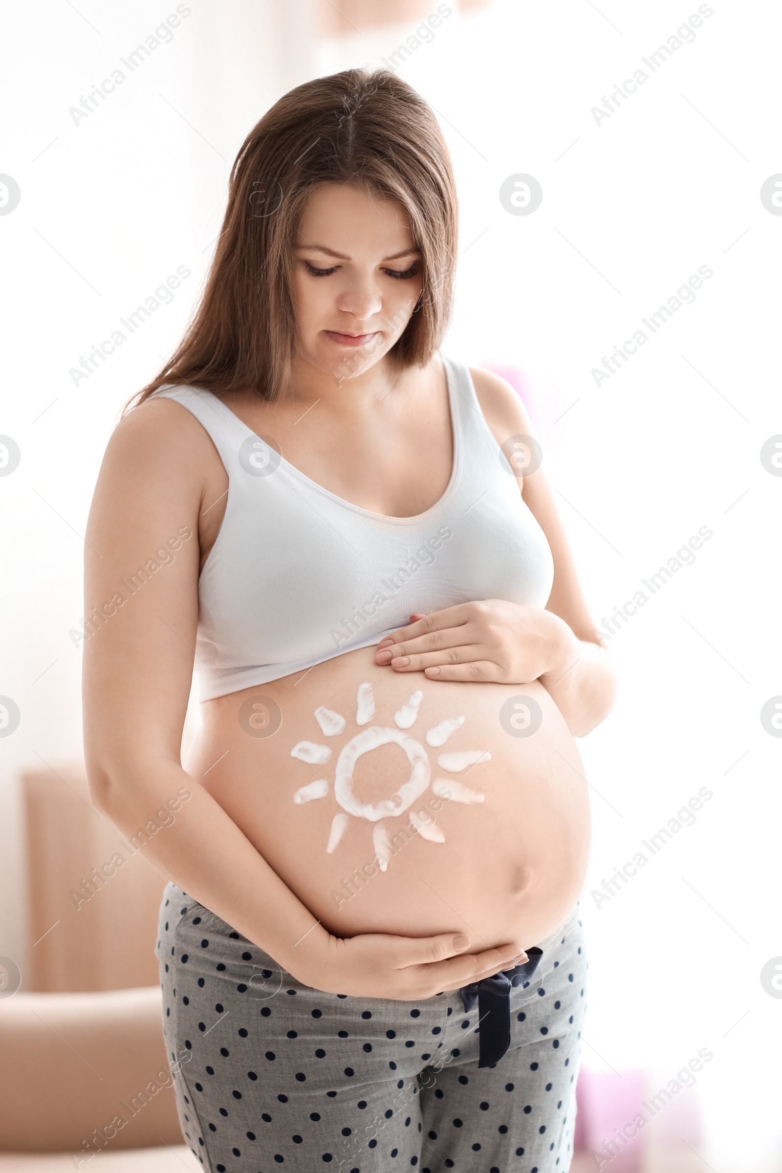 Photo of Pregnant woman with sun painted on her belly against blurred background