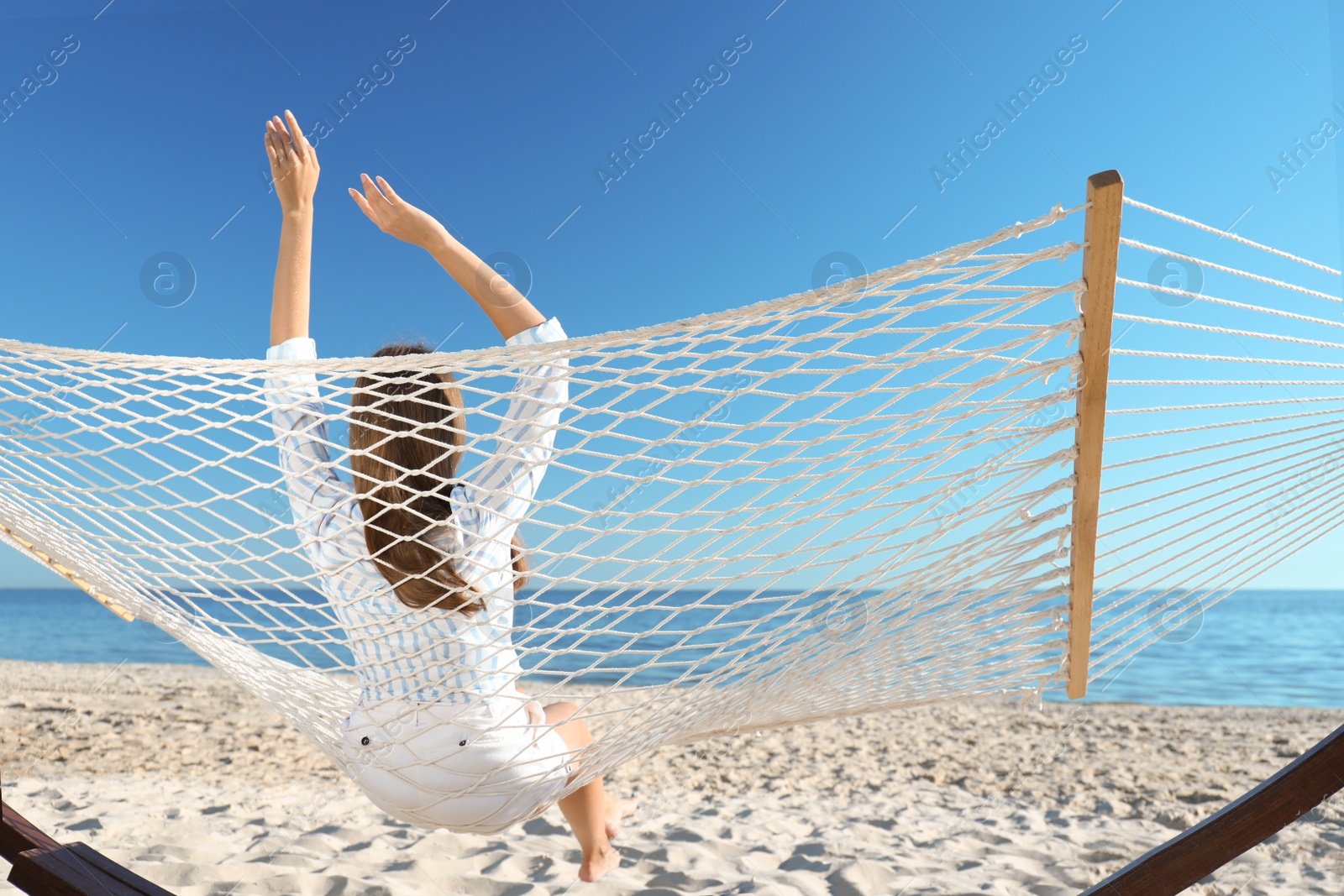 Photo of Young woman relaxing in hammock on beach