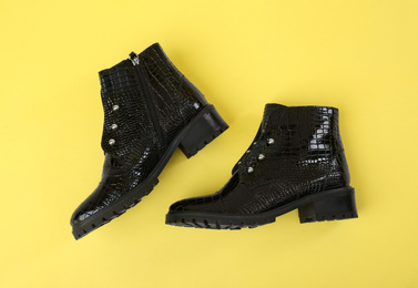 Pair of stylish ankle boots on yellow background, top view