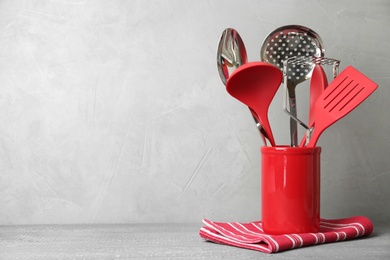 Photo of Holder with kitchen utensils on wooden table against light grey background. Space for text