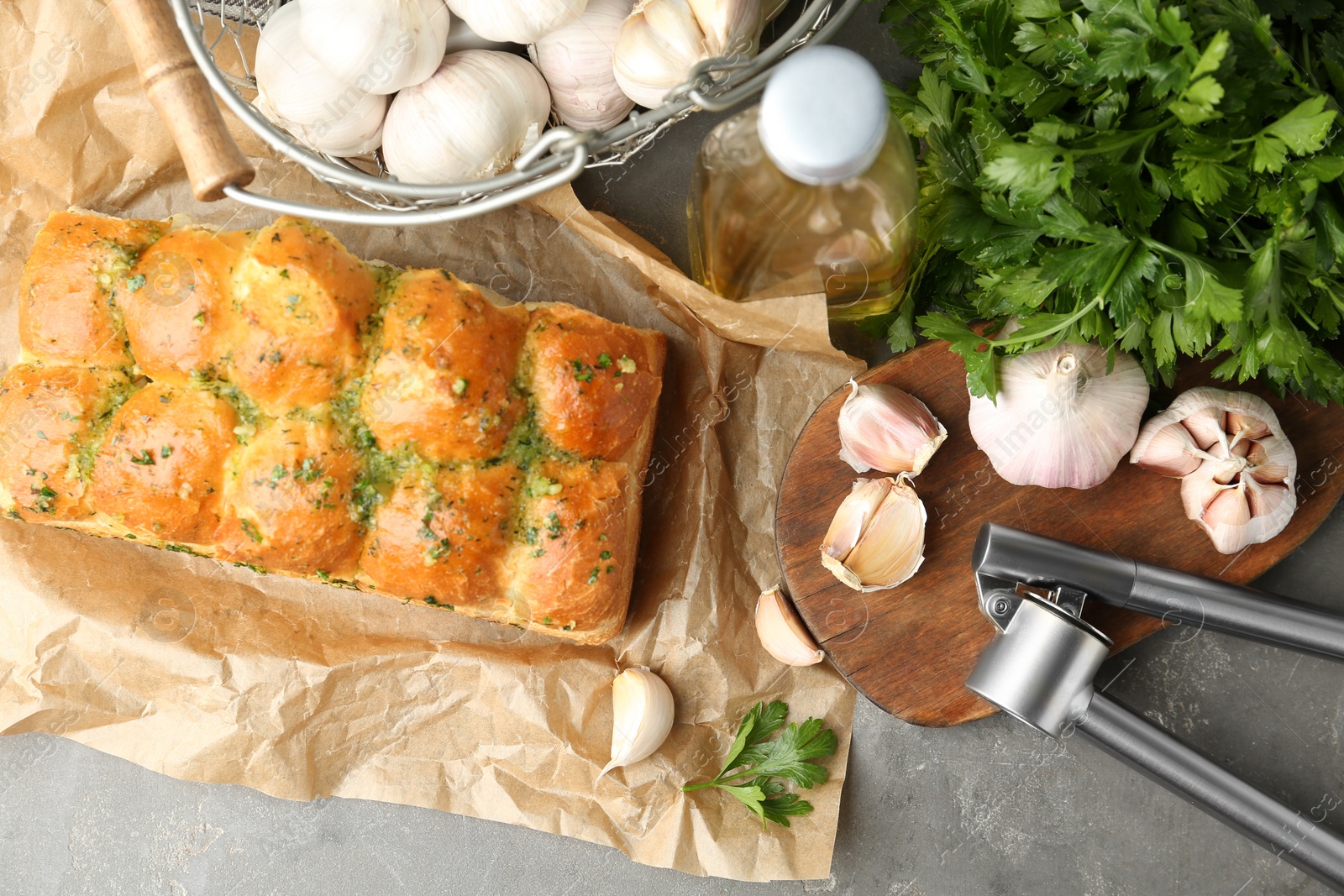 Photo of Buns of bread with garlic and herbs on grey table, flat lay