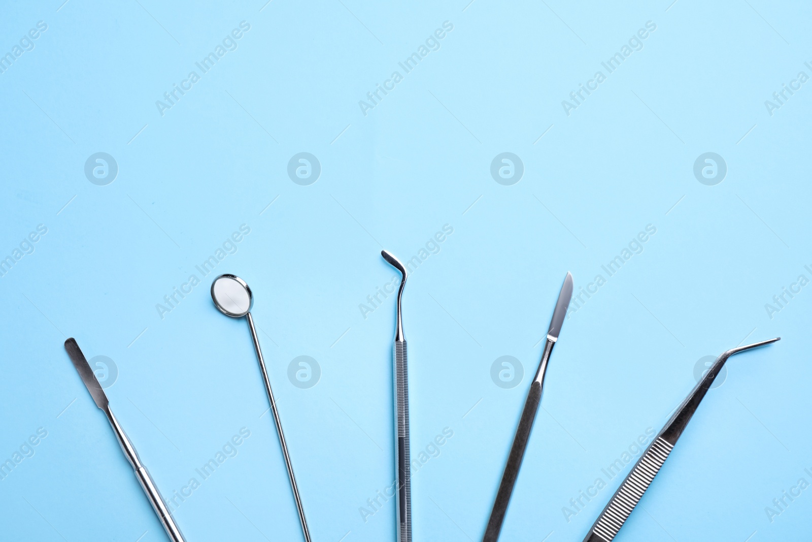 Photo of Set of different dentist tools on light blue background, flat lay. Space for text