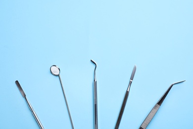Photo of Setdifferent dentist tools on light blue background, flat lay. Space for text