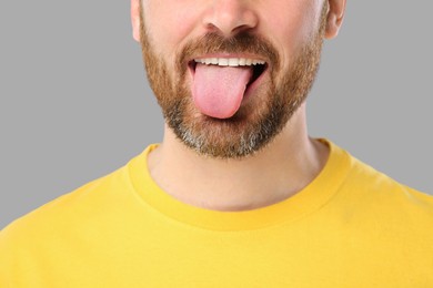 Photo of Man showing his tongue on gray background, closeup