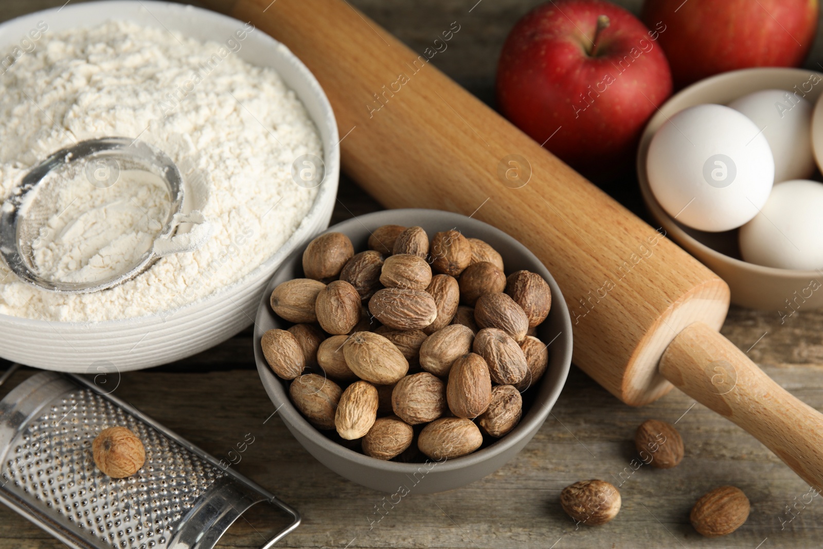 Photo of Nutmeg seeds and other ingredients for pastry on wooden table, above view