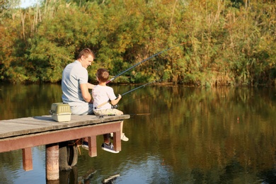 Dad and son fishing together on sunny day. Space for text