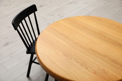 Stylish round table with black chair on floor