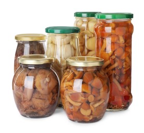 Jars with marinated mushrooms on white background