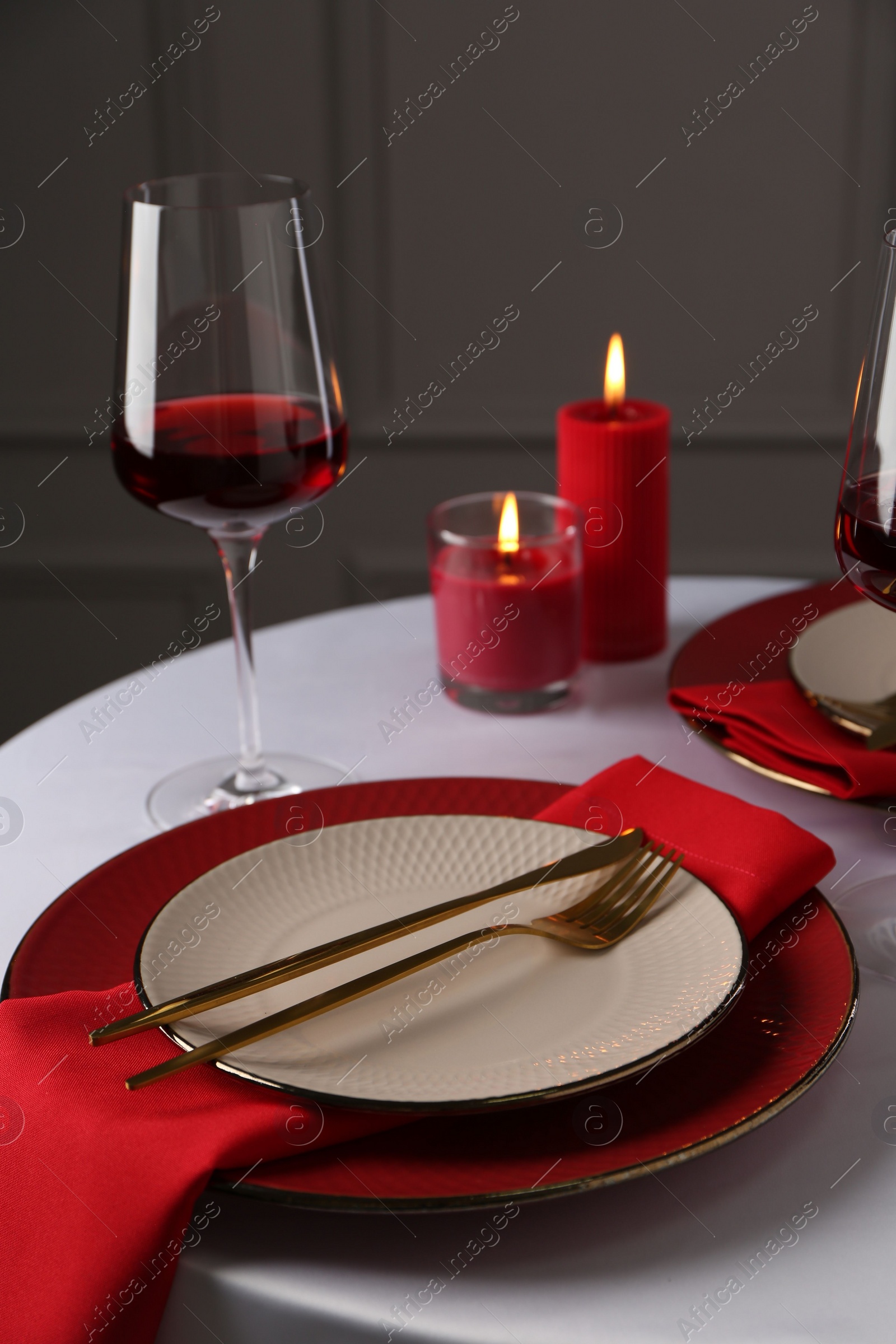 Photo of Place setting with candles on white table. Romantic dinner