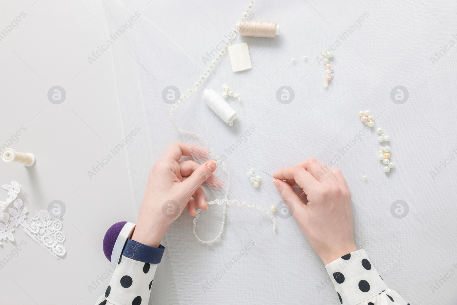 Photo of Dressmaker with sewing accessories at white table, top view