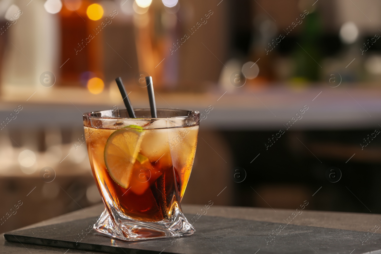 Photo of Cuba Libre cocktail on table in bar. Space for text