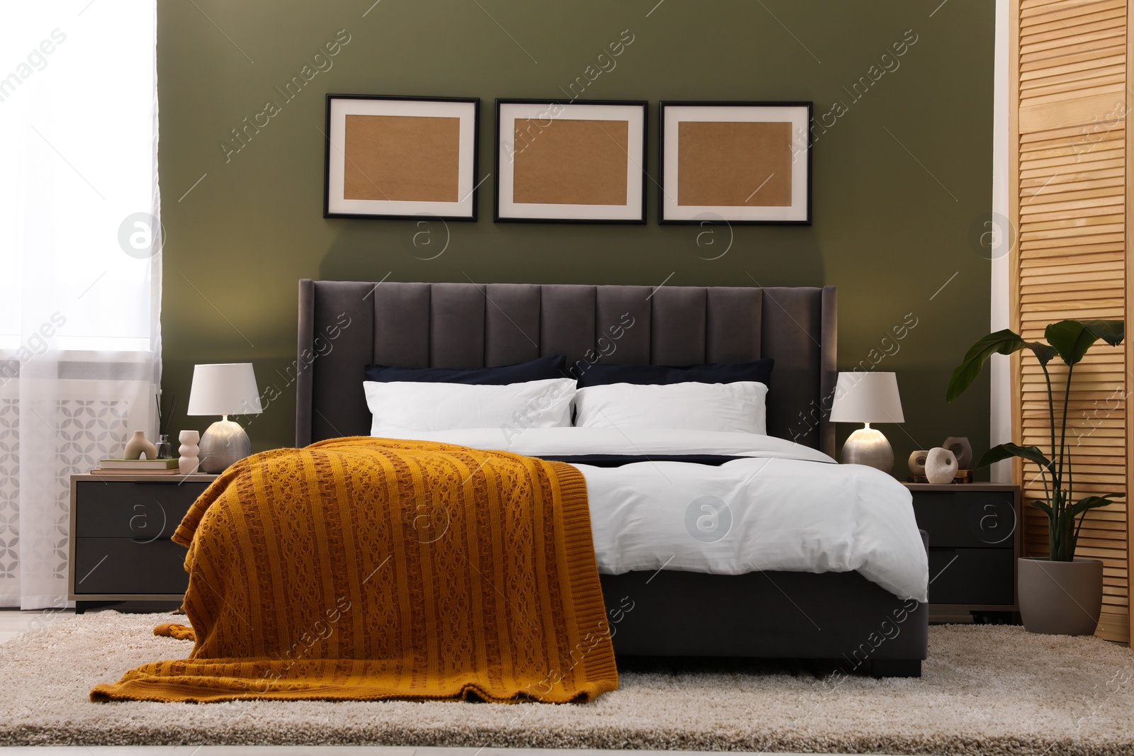 Photo of Large comfortable bed, lamps and houseplant in stylish room. Interior design